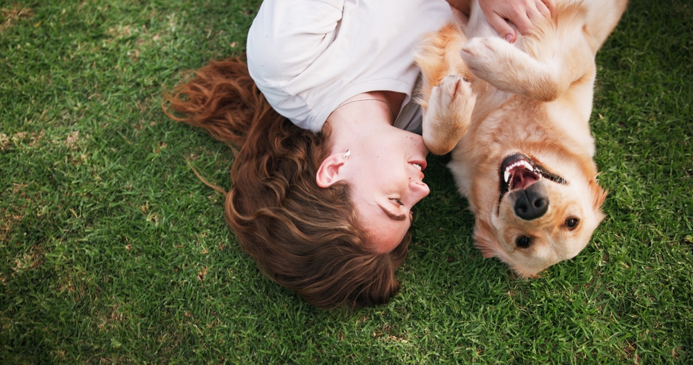 Woman,,relax,and,lying,with,dog,above,on,grass,field